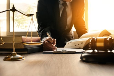 A lawyer filing out a document next to a gavel and scales